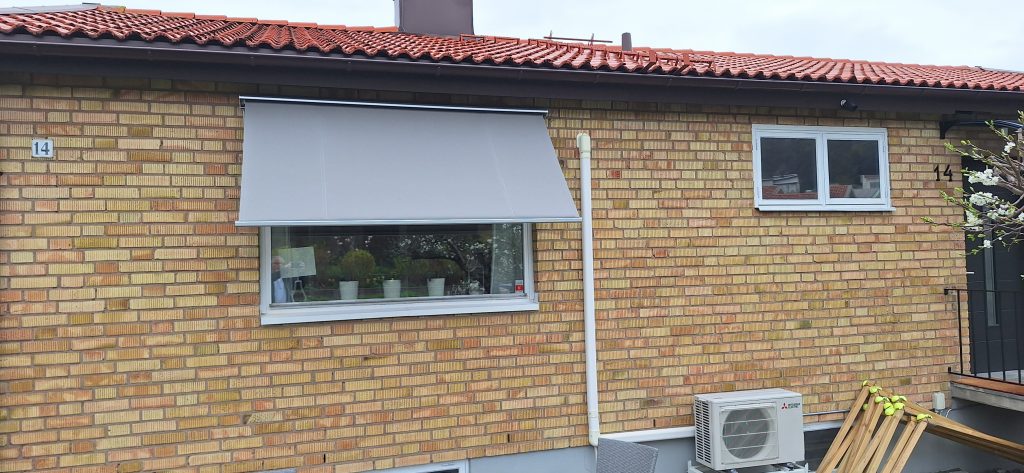 Grå markis på tegelhus.