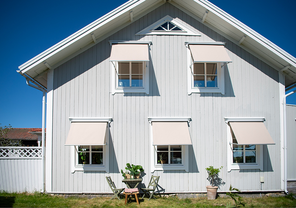 Fönstermarkis på grått hus.