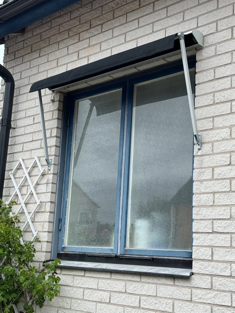 Svart markis på tegelhus.