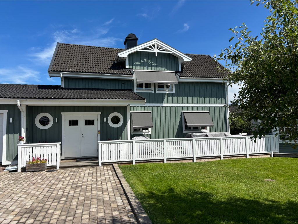 Grönt hus med grå markiser