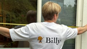 Person mäter ett fönster med måttband inför montering av fönstermarkis.