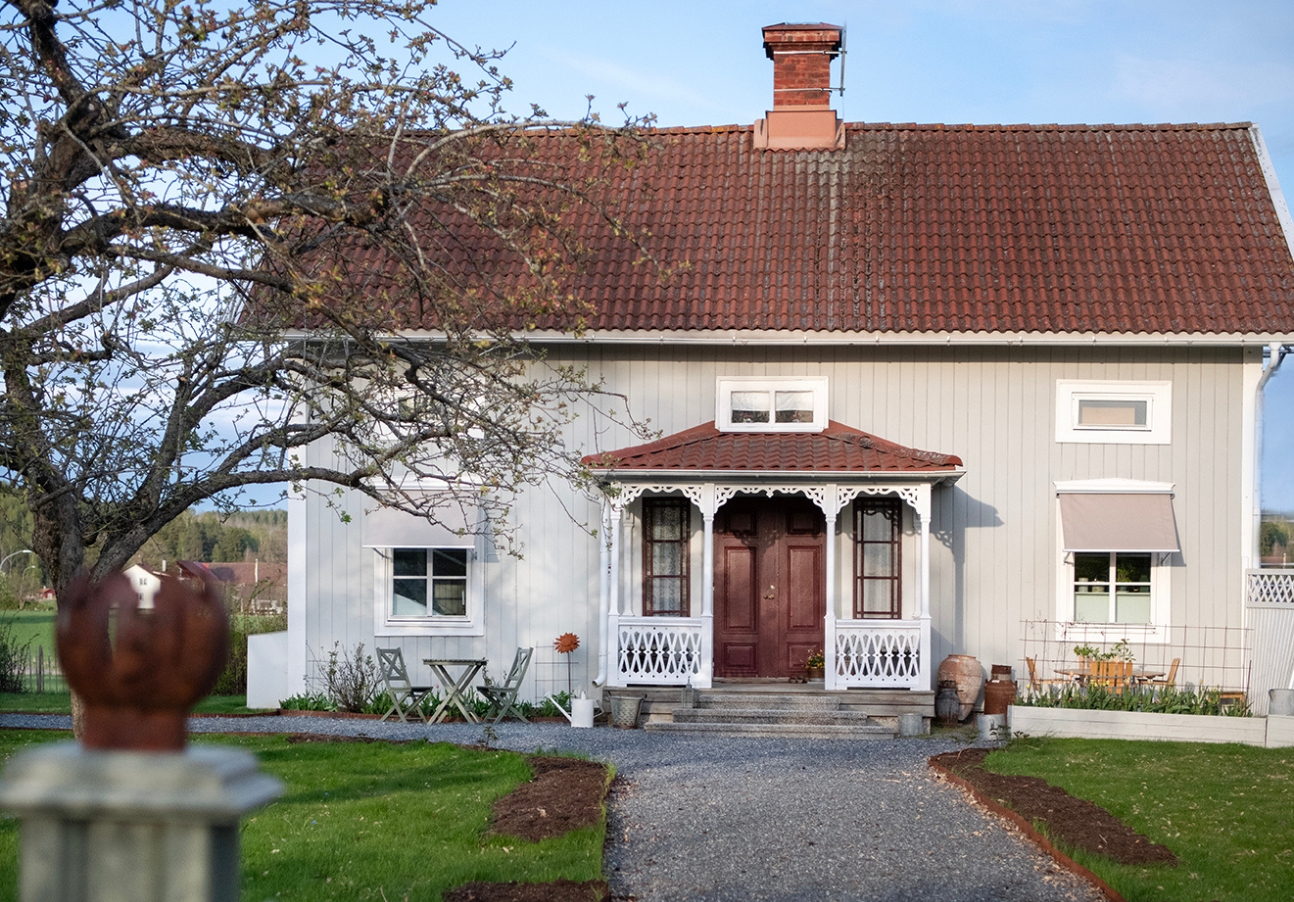Mörkgrå fönstermarkiser monterade på grönt hus. BILLY Markiser erbjuder måttanpassade modeller med snabb leverans inom 14 dagar – stilrent, hållbart och bekvämt solskydd för alla typer av fasader.