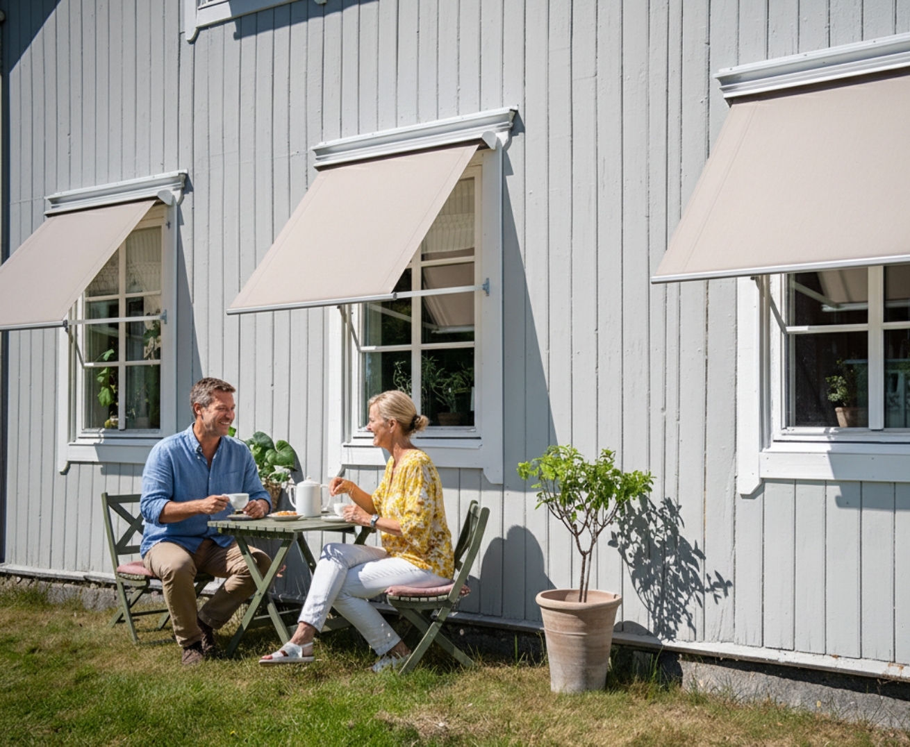 Måttanpassade bruna fönstermarkiser med motor, monterade på en elegant grå villa. Kombinerar exklusiv design med effektivt solskydd och bekväm elstyrning. En stilfull lösning från BILLY för moderna fasader.