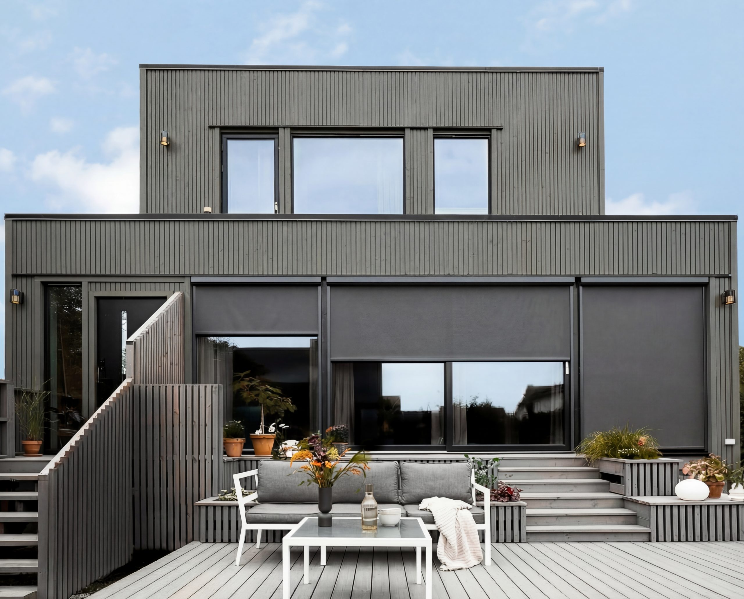 Markis av typen vertikalmarkis i svart på ett grått hus i Sverige. Flera vertikalmarkiser som skyddar mot insyn.